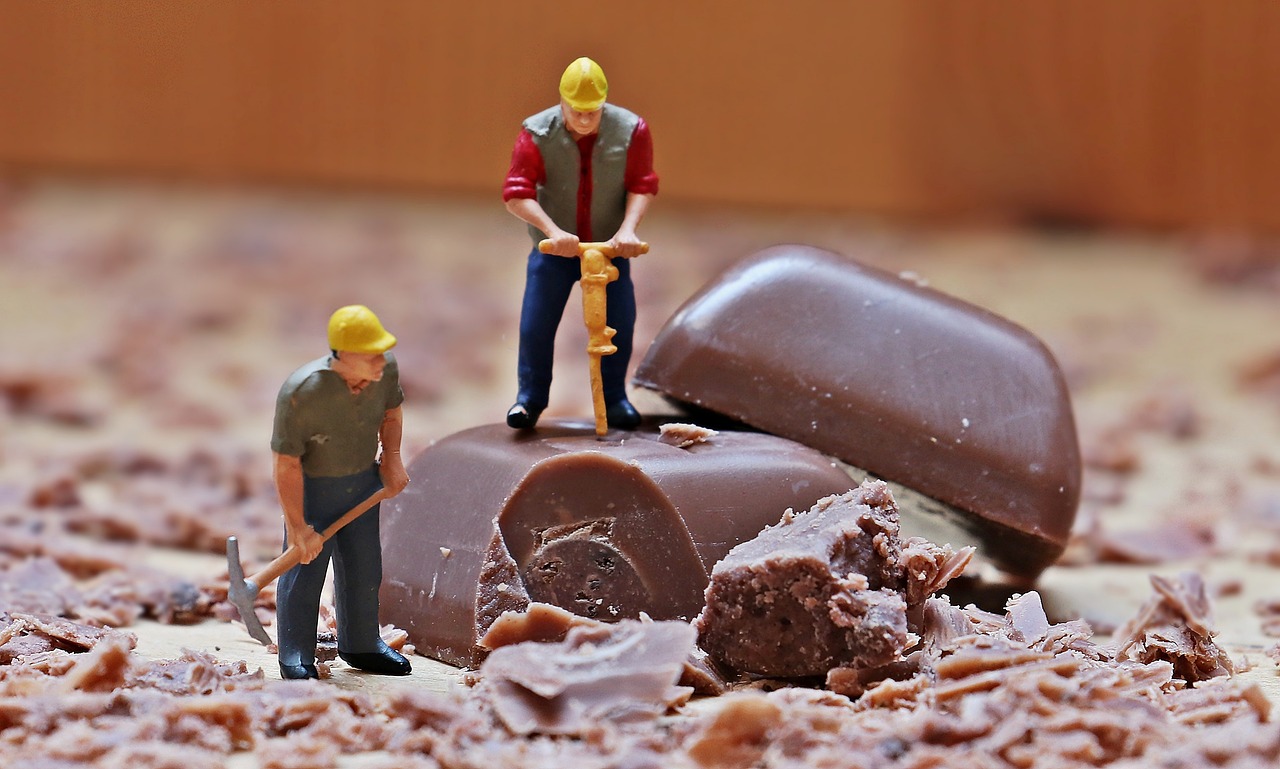 two miniature figures drilling squares of chocolate
